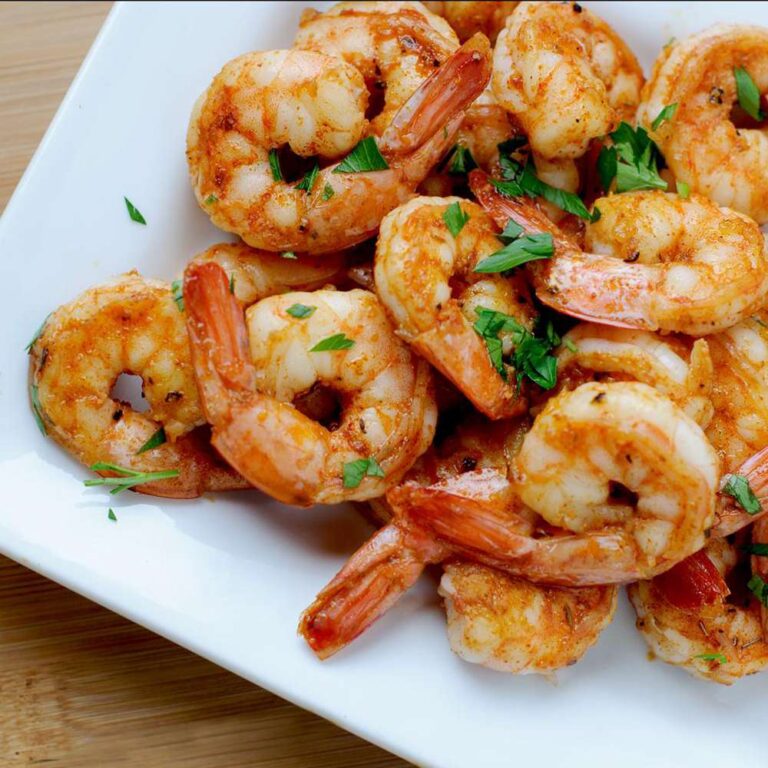 The photo showcases a plate of sautéed shrimp, seasoned with spices and garnished with chopped parsley, creating an appealing and flavorful seafood dish.